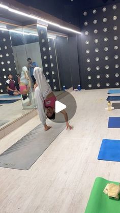 a person doing a handstand on a yoga mat in front of a mirror