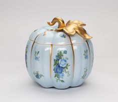 a blue and gold pumpkin shaped container with flowers on it