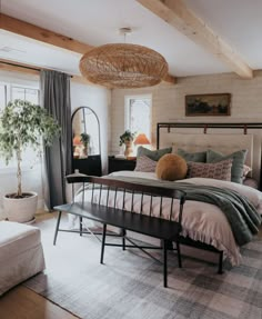 a bed room with a neatly made bed next to a window and a plant in the corner