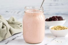 a smoothie in a mason jar with a spoon next to it and some cherries