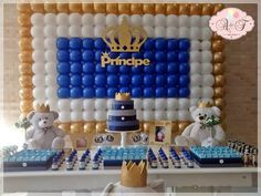 a table topped with blue and white cake next to balloons in the shape of a crown