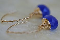 "Chalcedony open hoop earrings in cobalt blue and 14k gold fill. An elegant hand formed 14k gold filled arc shaped ear wire, made to look like a hoop earring, is wrapped with fine gauge 14k gold filled wire in a candy cane twist. Faceted cobalt blue chalcedony hangs from the ear wire. The heart shaped brioletts are lavishly wrapped in more 14k gold filled wire. Earrings hang approximately 1 1/2 \" (40mm) See more briolette dangle earrings here: http://www.etsy.com/shop/LHJewelryBoutique/search?s Blue Stone Earrings, Cobalt Blue Earrings, Chalcedony Earrings, Earrings Colorful, Open Hoop Earrings, Colorful Jewelry, Earrings Blue, Blue Chalcedony, Wire Earrings