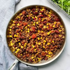 a pan filled with chili and corn on top of a table next to lettuce