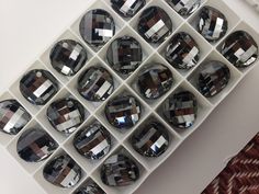 several rows of black diamond cut stones in a display case on a white table top