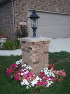 a lamp post surrounded by flowers in front of a house