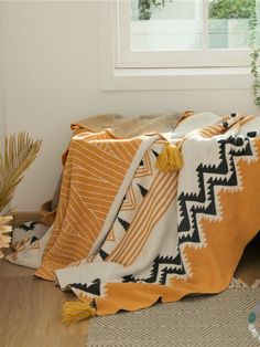 an orange and white blanket sitting on top of a wooden floor next to a window