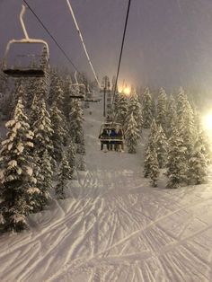 a ski lift with people on it going up the mountain in the snow covered trees