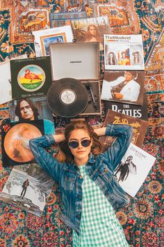 a woman laying on top of a rug covered in records