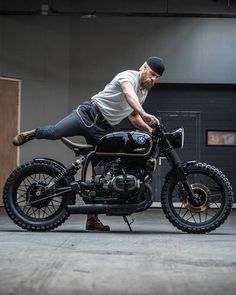 a man is doing tricks on a motorcycle in an indoor garage with his legs spread out