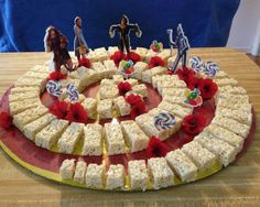 a cake that has been decorated with people and candy bars on the top, surrounded by small figurines