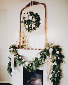 a fireplace decorated for christmas with wreaths and garland on it's mantel