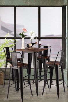 a table with four chairs and a vase on top of it next to a window