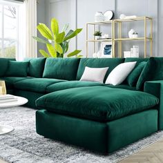 a living room with a large green couch and white pillows on the floor next to a coffee table