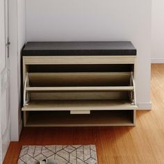 a wooden bench sitting in front of a white wall next to a rug on top of a hard wood floor