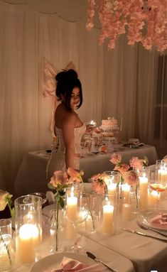 a woman standing in front of a table filled with candles