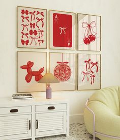 four red and white pictures hang on the wall above a small table with a lamp