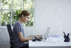 a woman sitting at a desk using a laptop computer