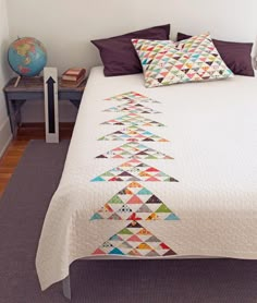 a white bed topped with a quilt and pillows