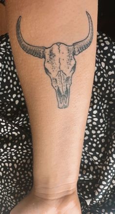 a woman's arm with a tattoo of a bull skull on the left side