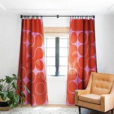 an orange chair sitting in front of a window next to a potted green plant