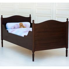 a small wooden bed with a teddy bear on it