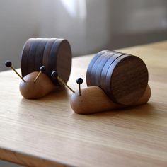 two small wooden objects sitting on top of a wooden table with pins stuck in them