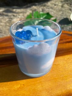 a glass filled with blue liquid sitting on top of a wooden table