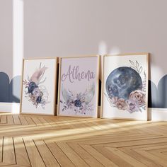 three framed art prints on a wooden floor in front of a wall with blue and pink flowers