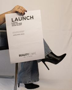 a woman sitting on a chair holding a sign that reads launch and can't wait for the salon to open