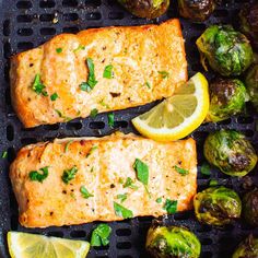 grilled salmon and brussel sprouts with lemon wedges on a grill