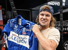 a man holding up a blue jacket in front of a store display case with an american legend logo on it