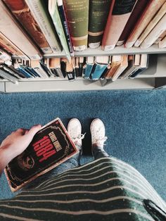 someone is sitting on the floor with their feet up in front of bookshelves