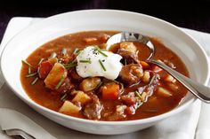 a white bowl filled with stew and sour cream