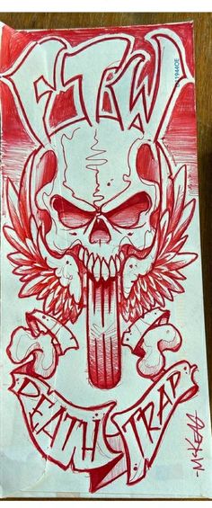 a red and white drawing of a skull with horns on it's head, in front of a wooden table