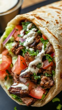 a burrito filled with meat, tomatoes and lettuce on top of a table