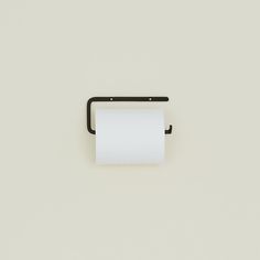 a roll of toilet paper hanging from a black metal holder on a white wall next to a toothbrush