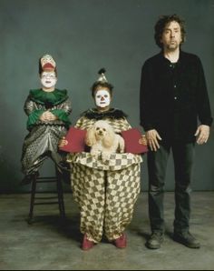 three people dressed up as clowns and one is holding a dog in a basket