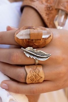 a close up of a person's hand holding a ring with a feather on it