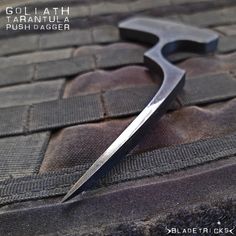 a close up of a knife on a piece of cloth with text overlay that reads, goliath brush dagger