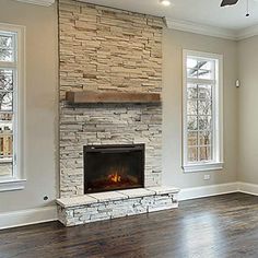 an empty living room with a fireplace and two windows