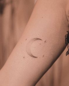 a woman's arm with a small crescent tattoo on the left side of her arm