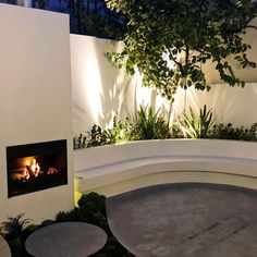 an outdoor fireplace in the middle of a garden at night