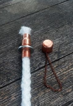 a spool of white wool is attached to a metal hook on a wooden surface