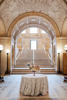 a white table topped with a vase filled with flowers on top of a marble floor