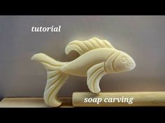 a soap carving of a fish sitting on top of a piece of wood with the words soap carving below it