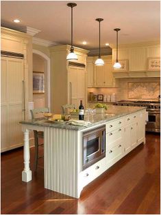 a large kitchen with an island in the middle of it and two lights hanging from the ceiling