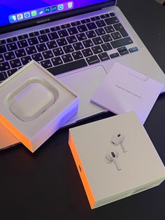 an open laptop computer sitting on top of a table next to two boxes with ear buds