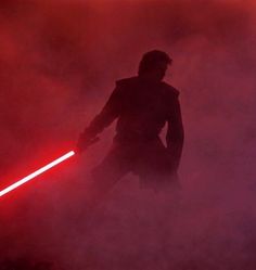 the silhouette of a person holding a light saber in front of a foggy background