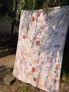 a quilt hanging from a tree outside in the sun