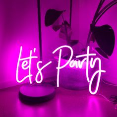 a neon sign that says let's party in front of a potted plant